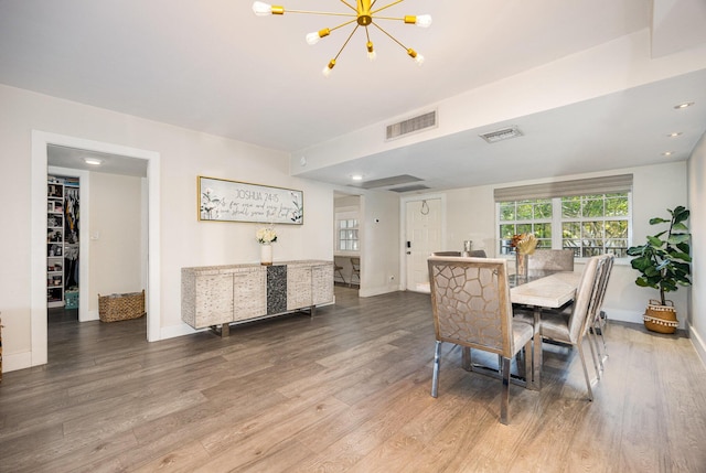 dining space with wood-type flooring and an inviting chandelier