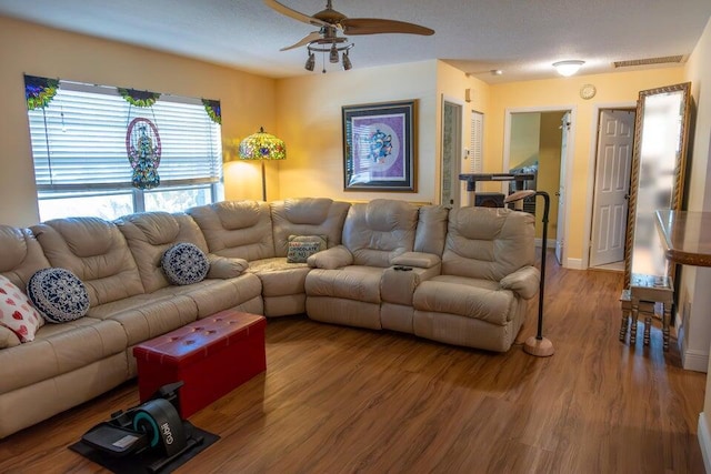 living room featuring hardwood / wood-style floors, ceiling fan, and a textured ceiling