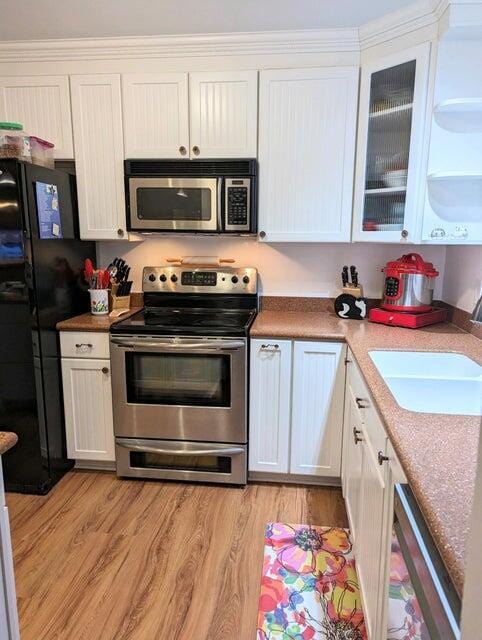 kitchen featuring white cabinets, sink, stainless steel appliances, and light hardwood / wood-style flooring