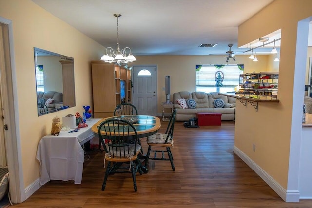 dining space featuring ceiling fan with notable chandelier and dark hardwood / wood-style floors