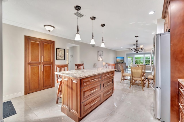 kitchen featuring stainless steel fridge, light stone counters, a notable chandelier, a center island, and hanging light fixtures