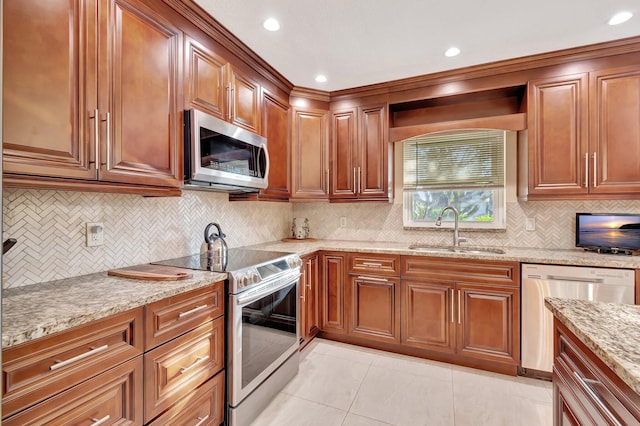 kitchen with sink, light tile patterned floors, appliances with stainless steel finishes, tasteful backsplash, and light stone counters