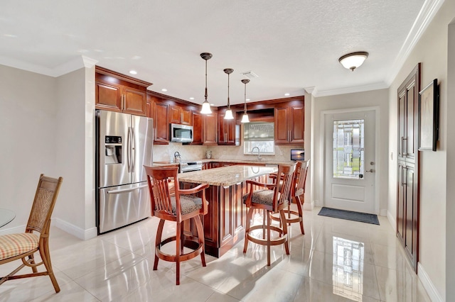 kitchen featuring tasteful backsplash, stainless steel appliances, sink, a kitchen island, and hanging light fixtures