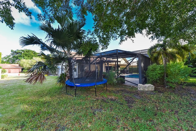 view of yard with glass enclosure and a trampoline