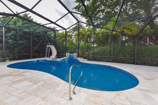 view of pool with glass enclosure, a patio area, and a water slide