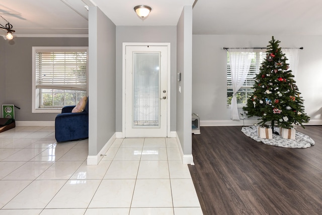 foyer entrance with light wood-type flooring, plenty of natural light, and ornamental molding