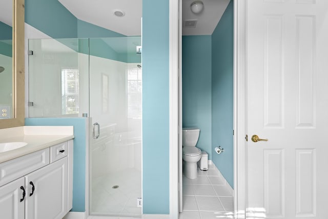 bathroom with tile patterned flooring, vanity, toilet, and walk in shower