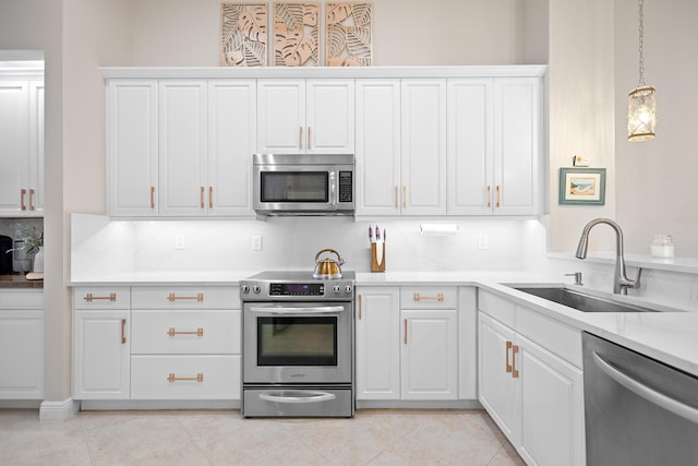 kitchen featuring white cabinets, hanging light fixtures, sink, light tile patterned floors, and appliances with stainless steel finishes