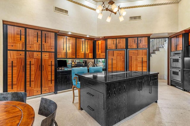 kitchen featuring a kitchen bar, a towering ceiling, black electric cooktop, a notable chandelier, and a center island