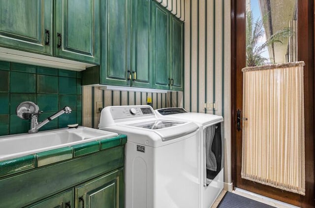 washroom with cabinets, washing machine and dryer, and sink