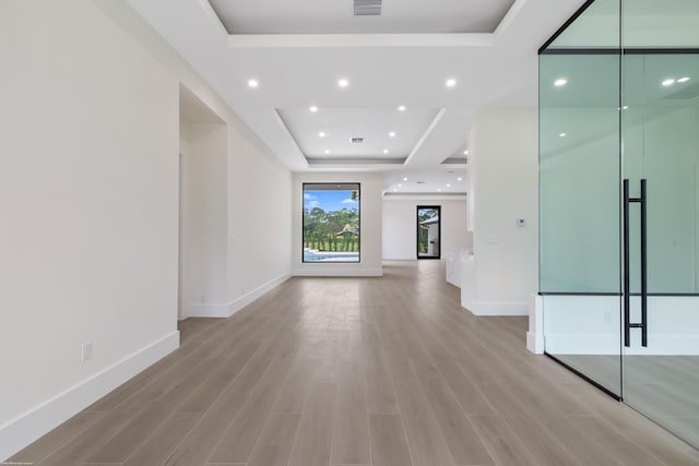 unfurnished living room with light hardwood / wood-style floors and a raised ceiling