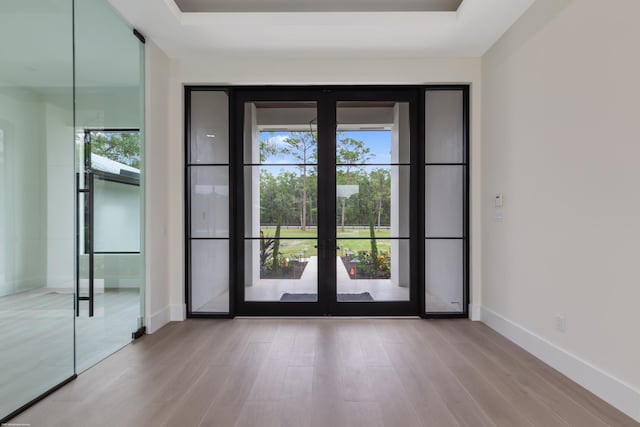 doorway to outside with a tray ceiling, french doors, and light hardwood / wood-style floors