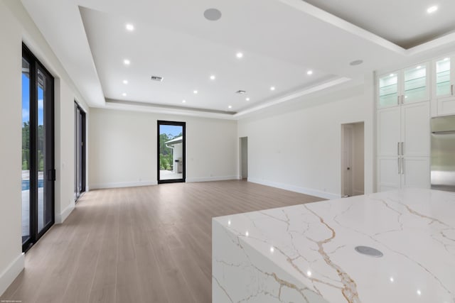 interior space with a tray ceiling and light hardwood / wood-style floors