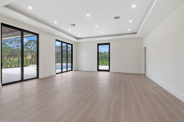 empty room featuring light wood-type flooring and a raised ceiling