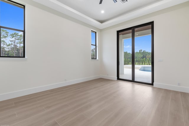 spare room featuring ceiling fan, a tray ceiling, and light hardwood / wood-style flooring