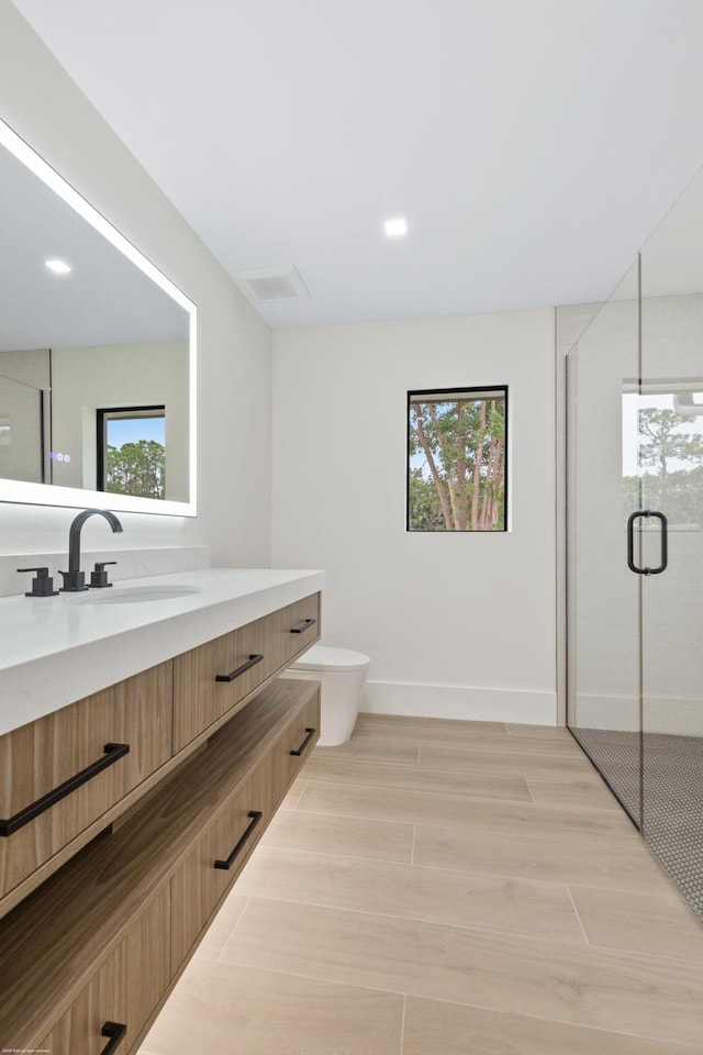 bathroom featuring vanity, toilet, walk in shower, and a healthy amount of sunlight