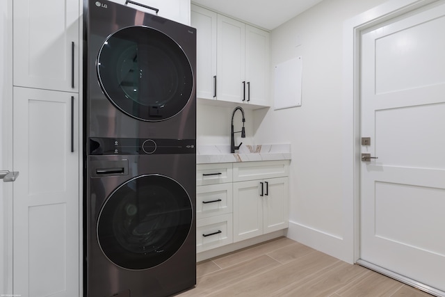 laundry room featuring stacked washer / drying machine, cabinets, and sink