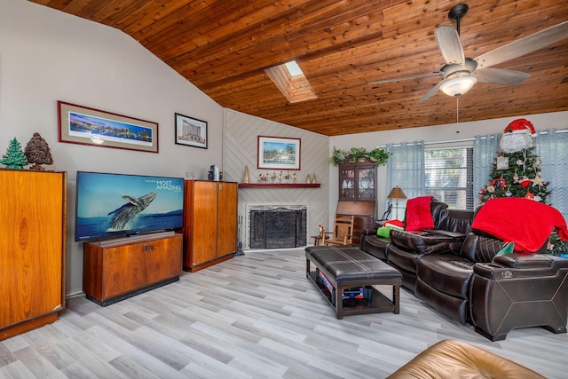 living room featuring wood ceiling, lofted ceiling with skylight, ceiling fan, light hardwood / wood-style flooring, and a fireplace