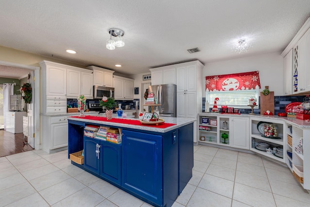 kitchen featuring a center island, white cabinets, stainless steel appliances, and blue cabinets