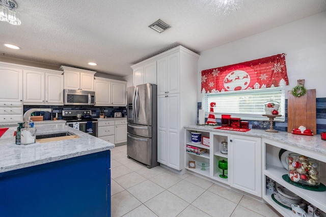 kitchen featuring appliances with stainless steel finishes, a textured ceiling, and white cabinetry