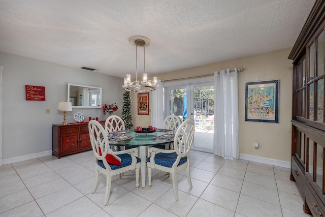 tiled dining room featuring a chandelier and a textured ceiling