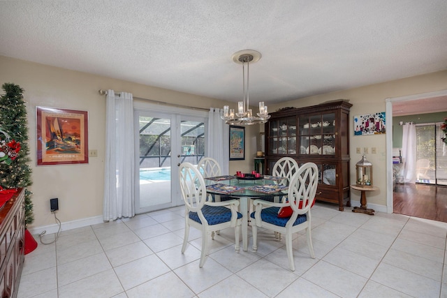 tiled dining area with french doors, a textured ceiling, and an inviting chandelier