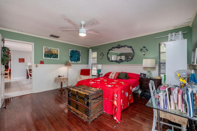 bedroom with a textured ceiling, hardwood / wood-style flooring, ceiling fan, and ornamental molding