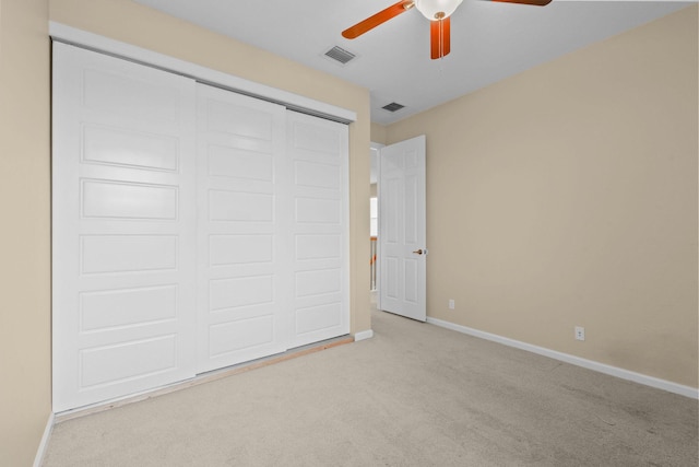 unfurnished bedroom with ceiling fan, light carpet, and a closet