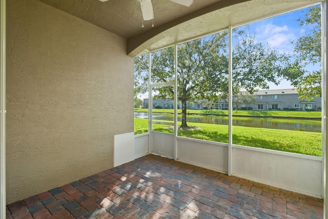 unfurnished sunroom featuring ceiling fan and a water view