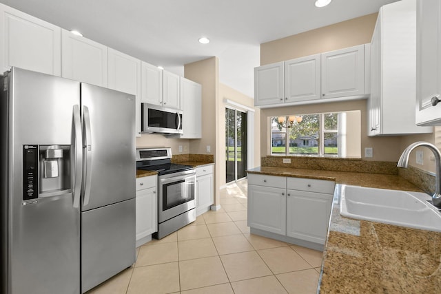 kitchen featuring white cabinetry, sink, stainless steel appliances, dark stone countertops, and light tile patterned flooring