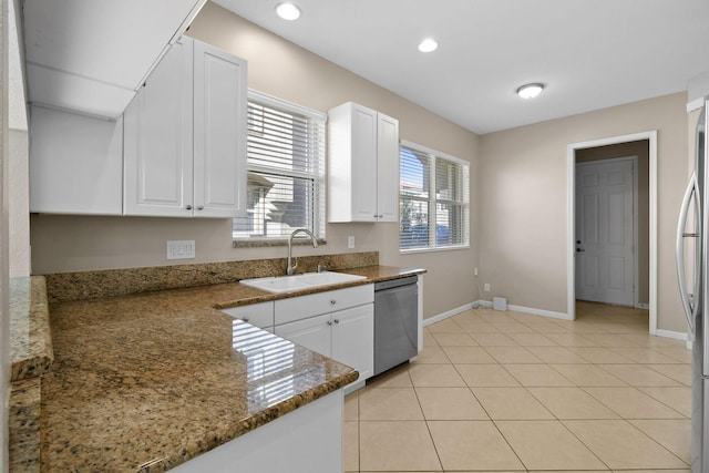 kitchen featuring sink, stainless steel appliances, white cabinets, dark stone counters, and light tile patterned flooring