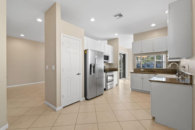 kitchen featuring white cabinetry, sink, light tile patterned flooring, and appliances with stainless steel finishes