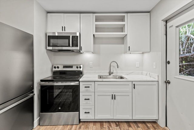 kitchen featuring white cabinetry, sink, light hardwood / wood-style floors, and appliances with stainless steel finishes