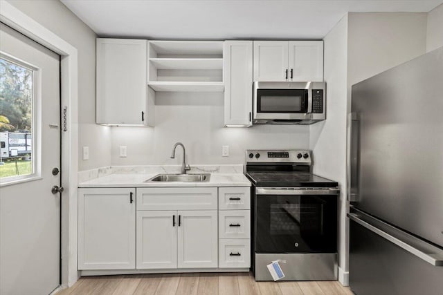 kitchen featuring a wealth of natural light, sink, white cabinets, and appliances with stainless steel finishes