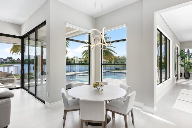 dining space featuring a notable chandelier, a water view, and a wealth of natural light