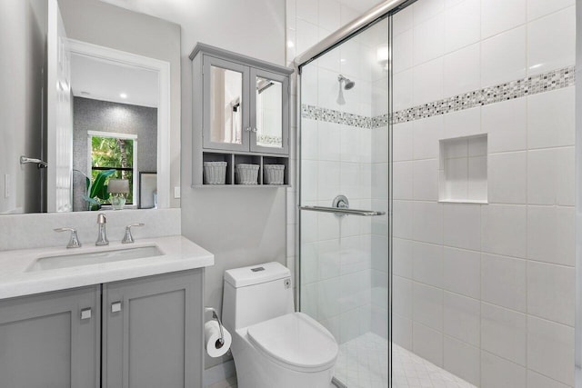 bathroom featuring vanity, a shower with shower door, and toilet