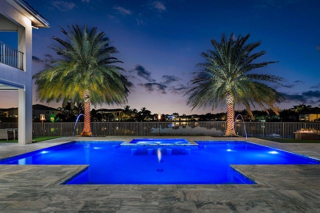 pool at dusk with an in ground hot tub