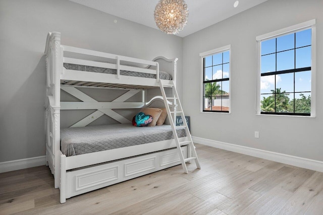 bedroom with a notable chandelier and light wood-type flooring