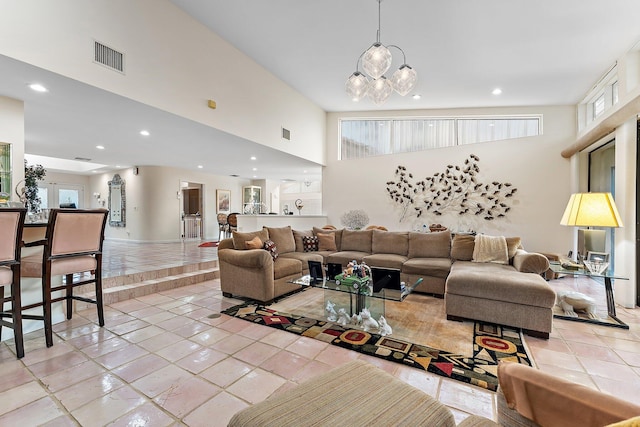 tiled living room featuring a chandelier and a high ceiling