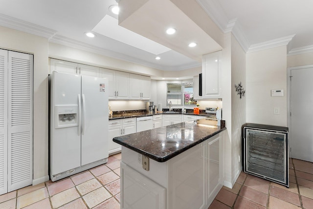 kitchen with white appliances, crown molding, white cabinetry, dark stone countertops, and wine cooler