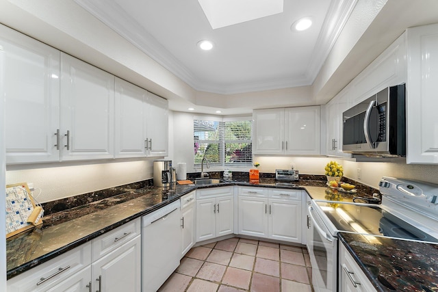 kitchen featuring white appliances, white cabinets, sink, a skylight, and ornamental molding