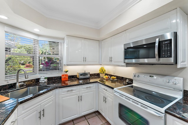 kitchen with electric stove, sink, white cabinets, and plenty of natural light