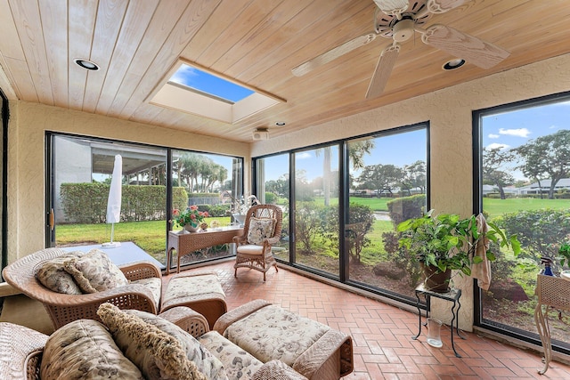 sunroom featuring a skylight, ceiling fan, wooden ceiling, and a wealth of natural light