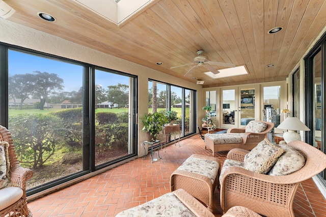 sunroom / solarium featuring ceiling fan, a skylight, plenty of natural light, and wood ceiling