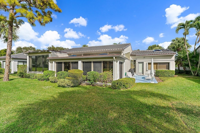 back of property featuring a lawn, a sunroom, and a patio