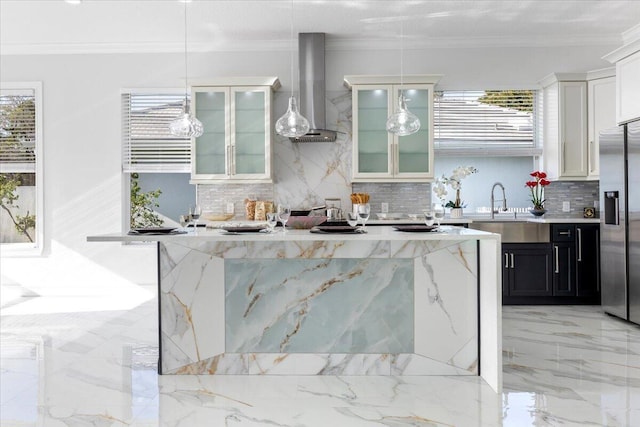 kitchen featuring wall chimney exhaust hood, stainless steel fridge, a healthy amount of sunlight, and hanging light fixtures