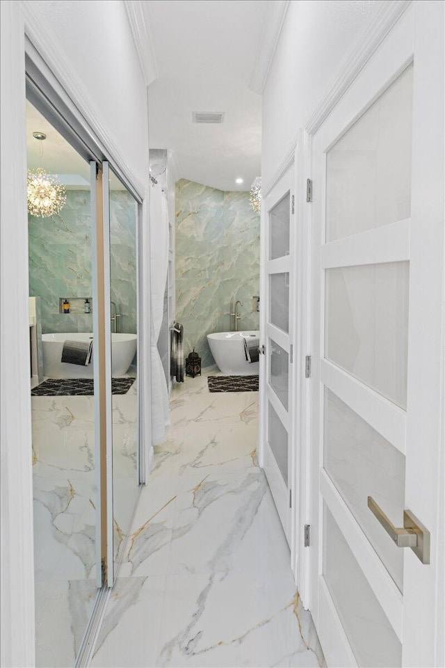 bathroom featuring a bathing tub, a chandelier, tile walls, and ornamental molding