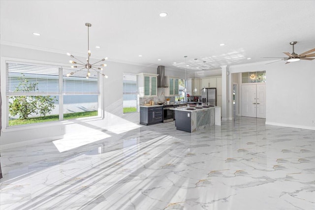 kitchen featuring hanging light fixtures, wall chimney range hood, stainless steel refrigerator with ice dispenser, a kitchen island, and ornamental molding