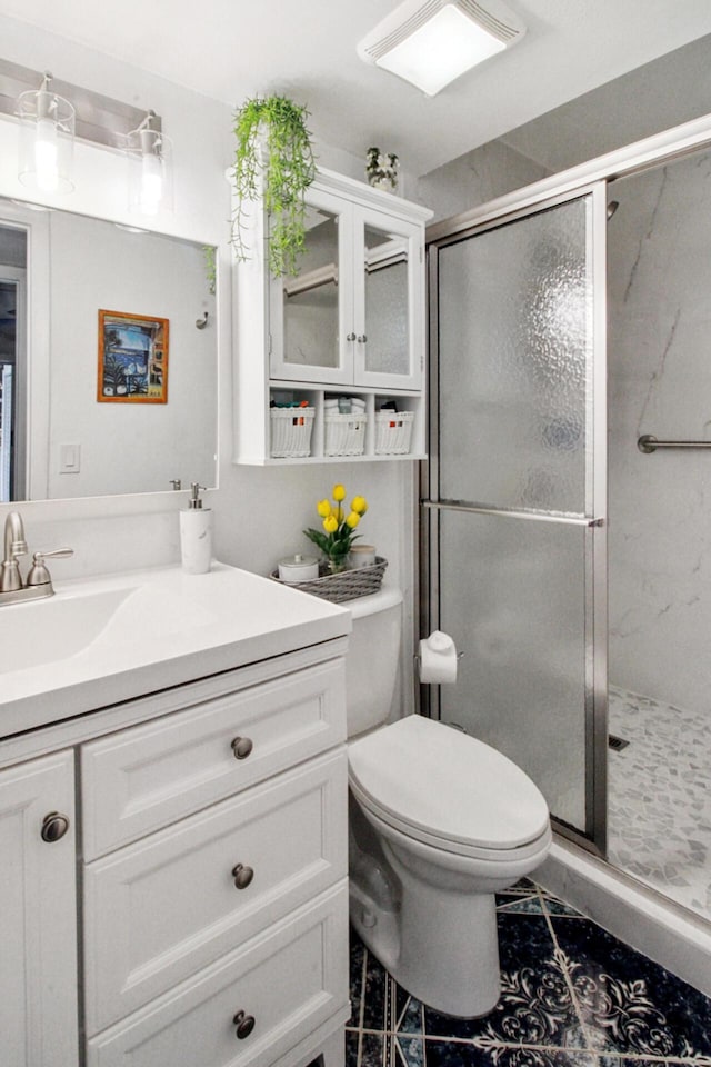 bathroom with tile patterned floors, vanity, a shower with shower door, and toilet