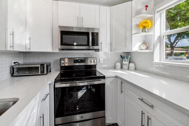 kitchen featuring white cabinets, backsplash, and stainless steel appliances